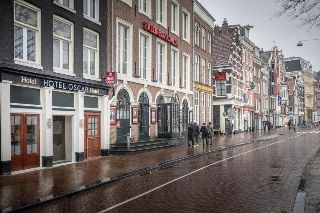 Una calle de la ciudad bajo la lluvia con gente caminando por ella en Hotel Oscar, en Ámsterdam