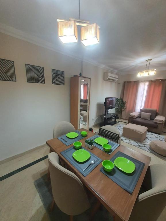 un soggiorno con tavolo in legno e piastre verdi di TREE Serviced Apartment -2BHK Self check-in a Il Cairo