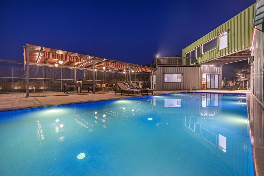 a large swimming pool at night at ELIVAAS Hidden Oasis 4BHK with Pool, Mud House & Container House in Dhauj