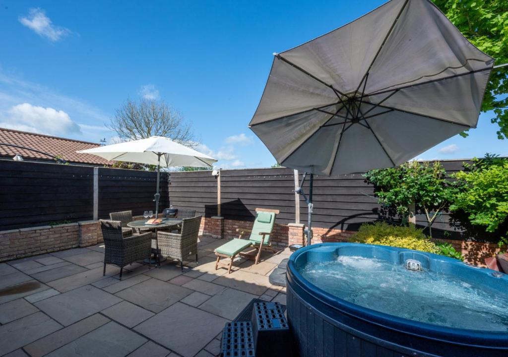 a patio with a hot tub and an umbrella at Pheasant Lodge in Reepham