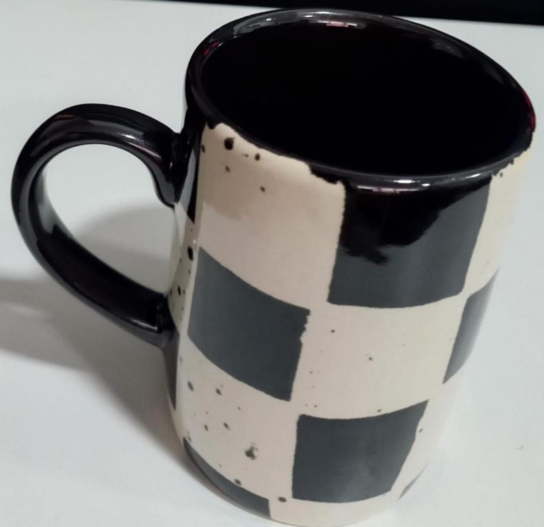 uma caneca de café preta e branca sobre uma mesa em tharuka em Moratuwa