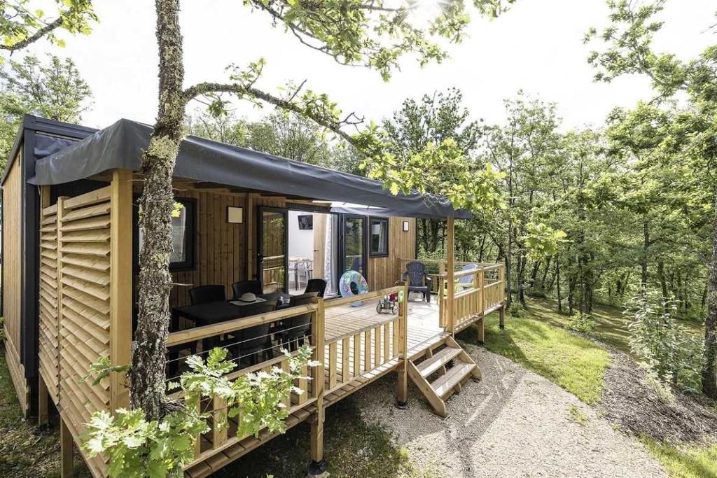 una cabina nel bosco con un ampio ponte di Camping 4 étoiles - Piscine - eeihec a Loupiac