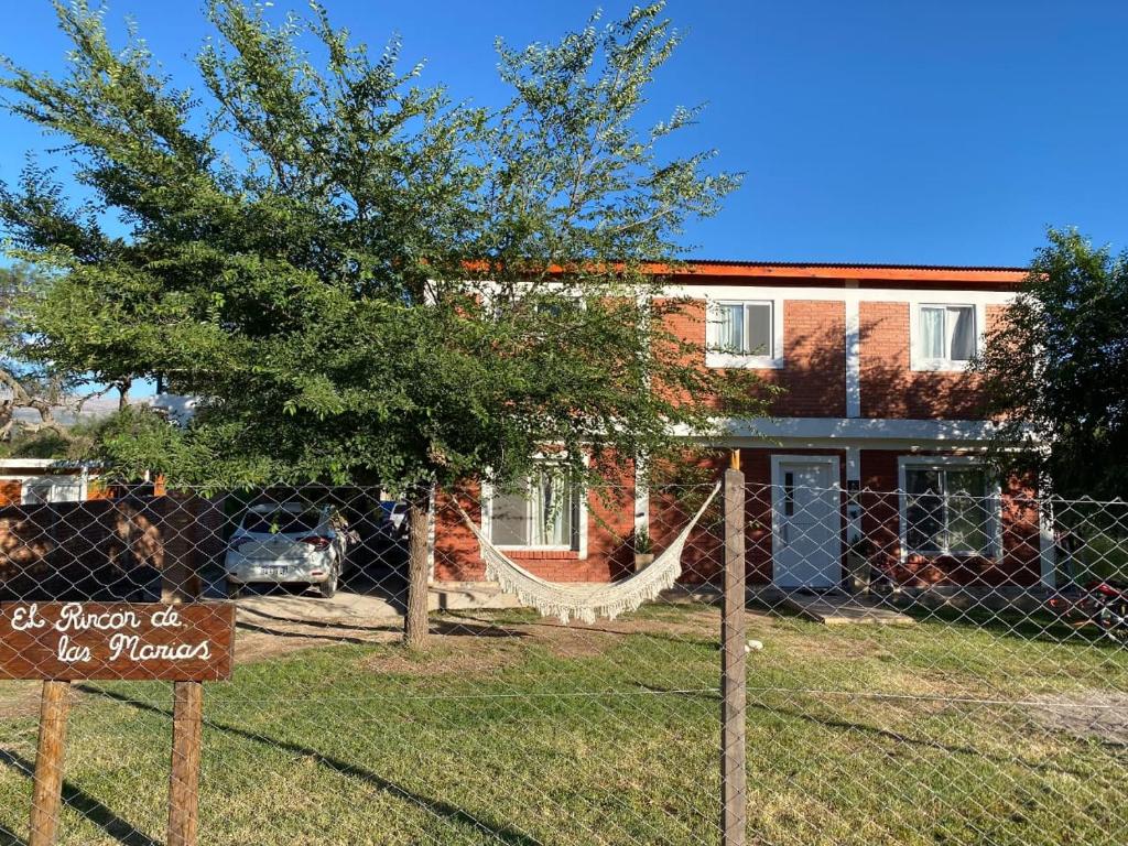 a fence with a hammock in front of a house at El Rincon de las Marias Casa en Planta Alta in San Lorenzo