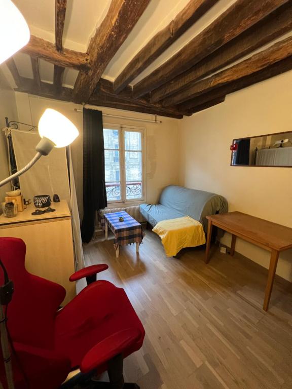 un salon avec une chaise rouge et un canapé dans l'établissement Cozy studio Bastille, à Paris