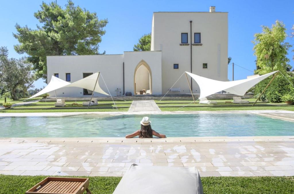 una persona sentada en una piscina frente a un edificio en Masseria Ceratonia by Raro Villas, en Baia Verde