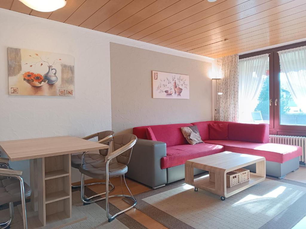 a living room with a red couch and a table at 2-Raum FeWo Arnika - Hallenbad & Sauna in Fischen