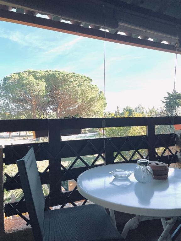 d'une table et de chaises blanches sur un balcon avec fenêtre. dans l'établissement Appart clim wifi - 2 à 6 pers - piscines - parking, à Fitou