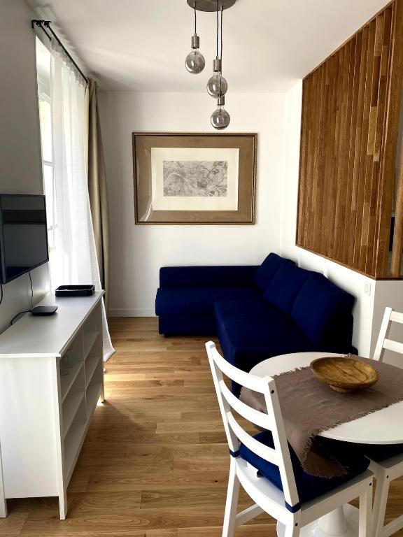 un salon avec un canapé bleu et une table dans l'établissement La Petite Paroisse, à Versailles