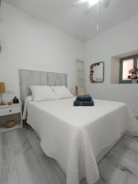 a white bedroom with a large white bed and a table at Casa Encarnita in Arcos de la Frontera
