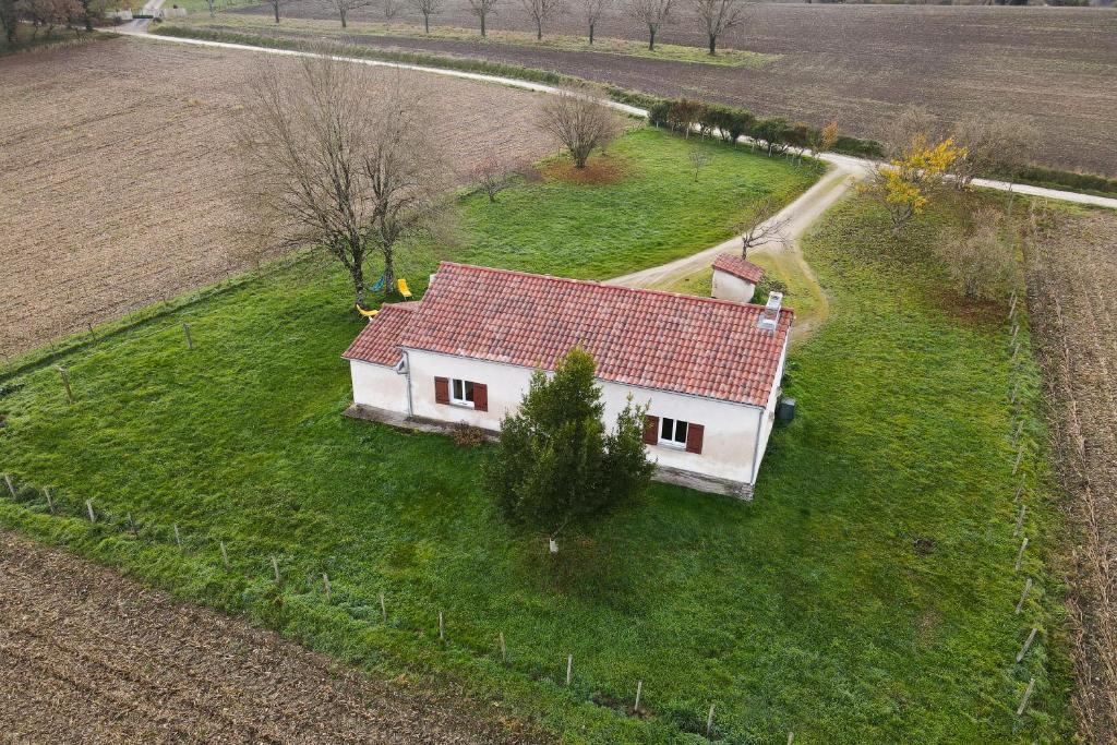 une petite maison blanche avec un toit rouge dans un champ dans l'établissement La Grande Métairie, à Villetoureix