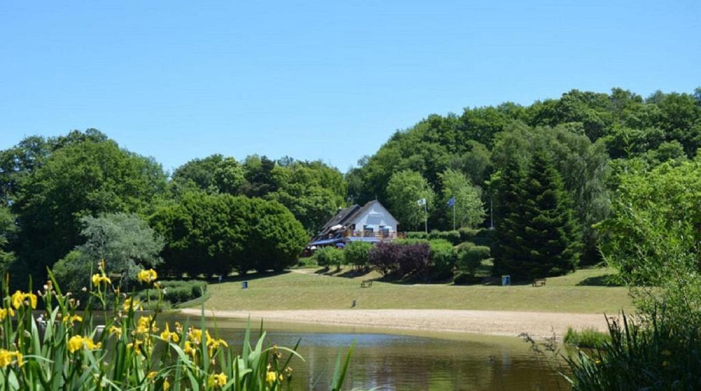 a house on a hill next to a body of water at L'Aquarelle - Camping in La Souterraine