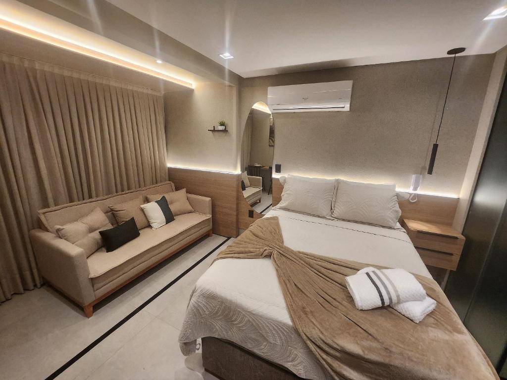 a small bedroom with a bed and a couch at Get By Side na Beira mar do Caribessa Jardim Oceania in Tambaú