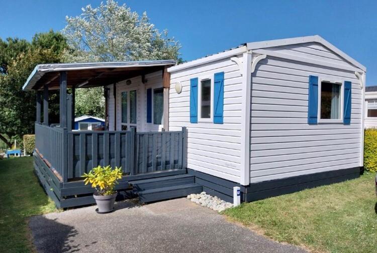 a small white house with blue windows and a porch at 600m de la plage - Mobilhome Loka 4 personnes camping Goelands 3 étoiles in Saint-Martin-Plage