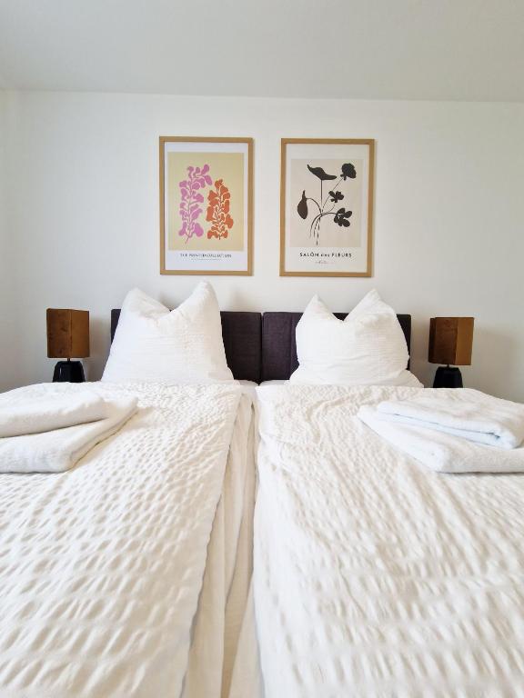 two beds with white sheets and two pictures on the wall at ARGENTA Living 129 in Künzell