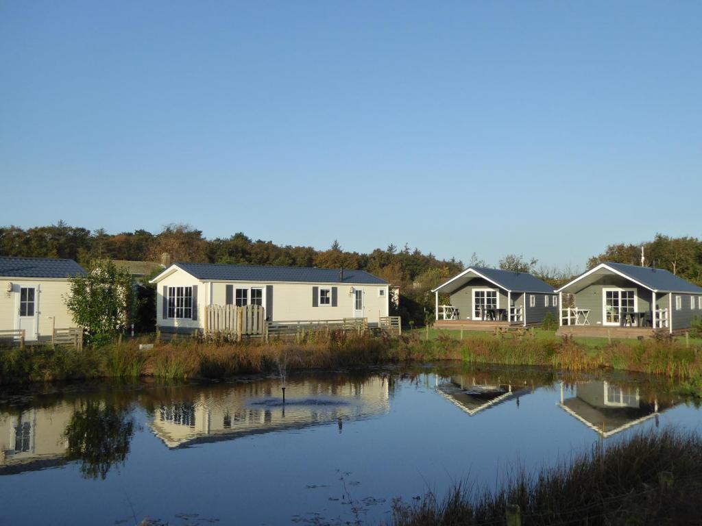 uma fila de casas móveis num lago em Vakantiepark Dennenoord em Den Burg