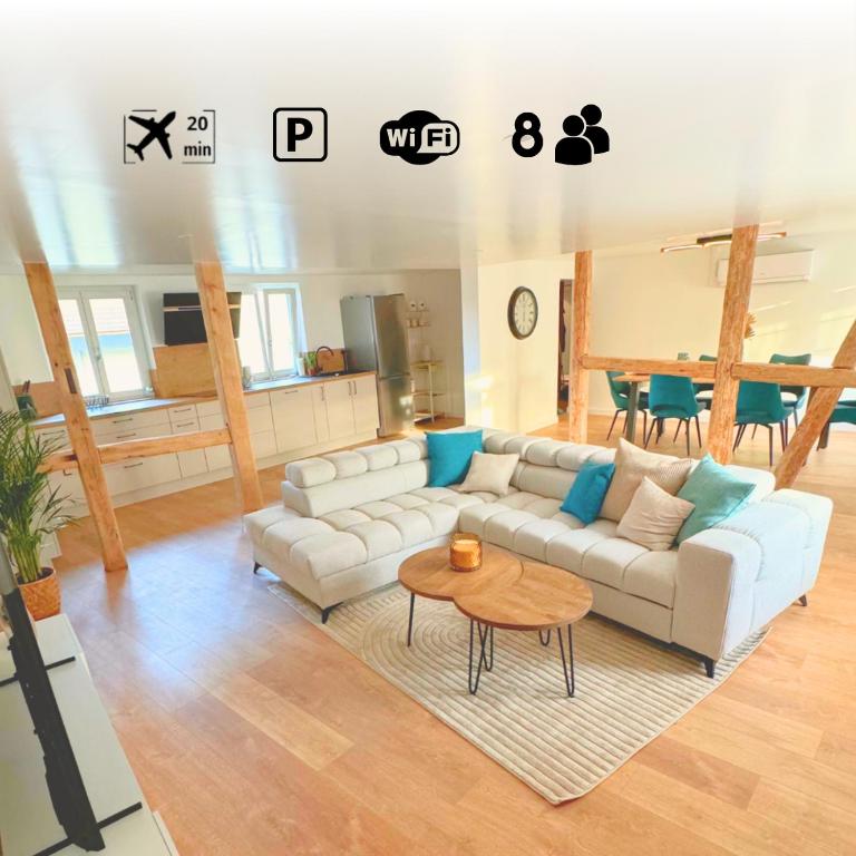 a living room with a white couch and a table at Grand appartement chaleureux in Steinbrunn-le-Bas