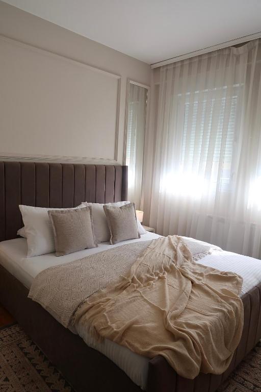 Una cama con sábanas blancas y almohadas en un dormitorio. en The Modern Flat, en Pristina