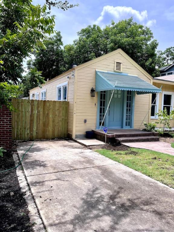 a yellow house with a fence and a blue door at Charming 2-bedroom Cottage in San Antonio