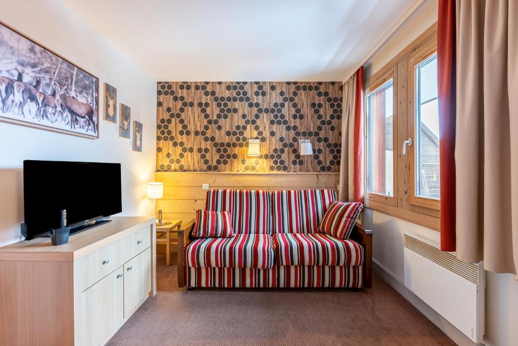 Il comprend un salon avec une chaise et une télévision à écran plat. dans l'établissement Séjour à la montagne - Soldanelle, à La Plagne Tarentaise