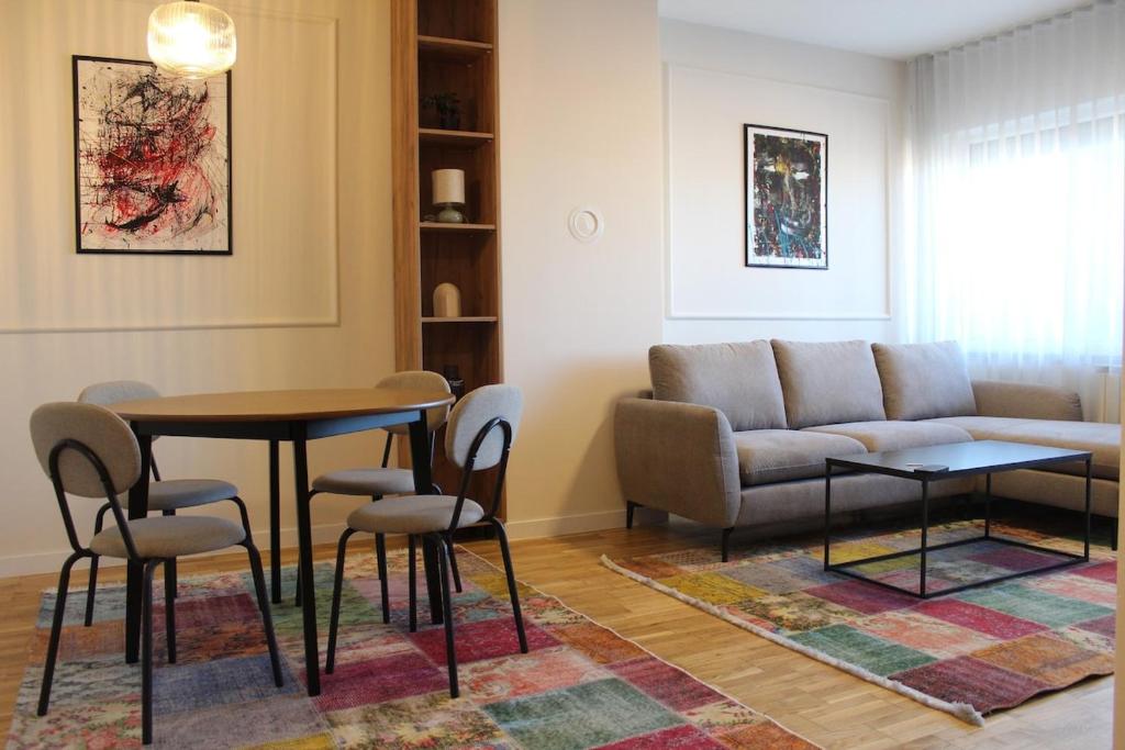 a living room with a couch and a table and chairs at Sun Apartments in Pristina