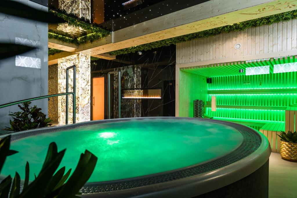 a bath tub in a bathroom with green lighting at Góralski Resort Family & SPA in Białka Tatrzańska