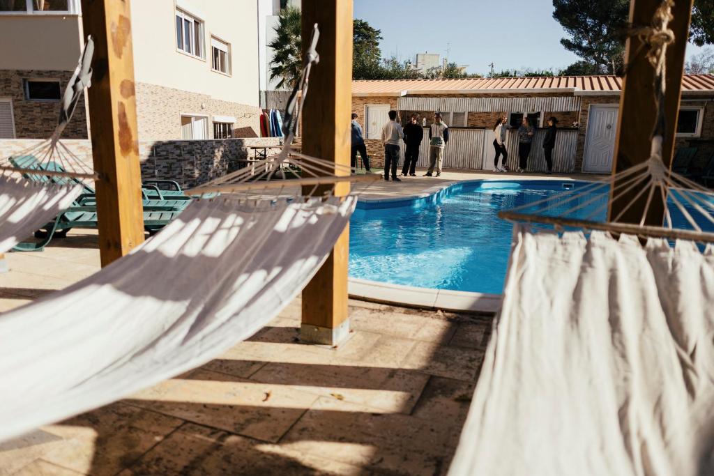 a group of hammocks next to a swimming pool at Lisbon Surf Hostel in Carcavelos