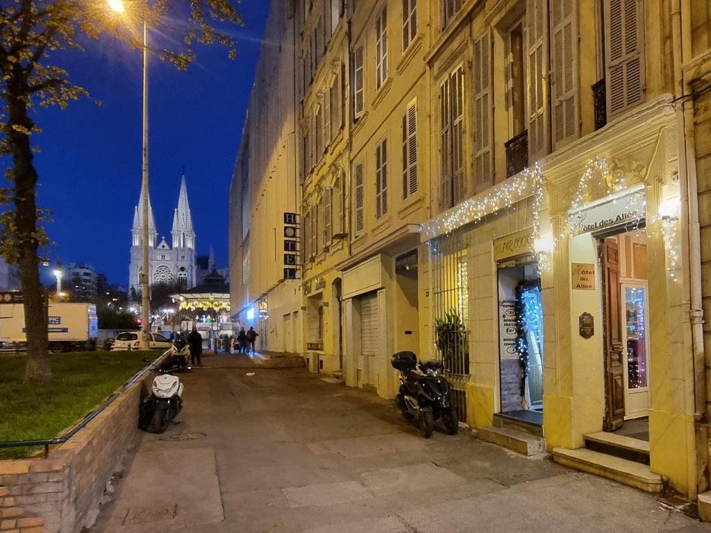 a city street with buildings and a cathedral at night at Hôtel des allées in Marseille