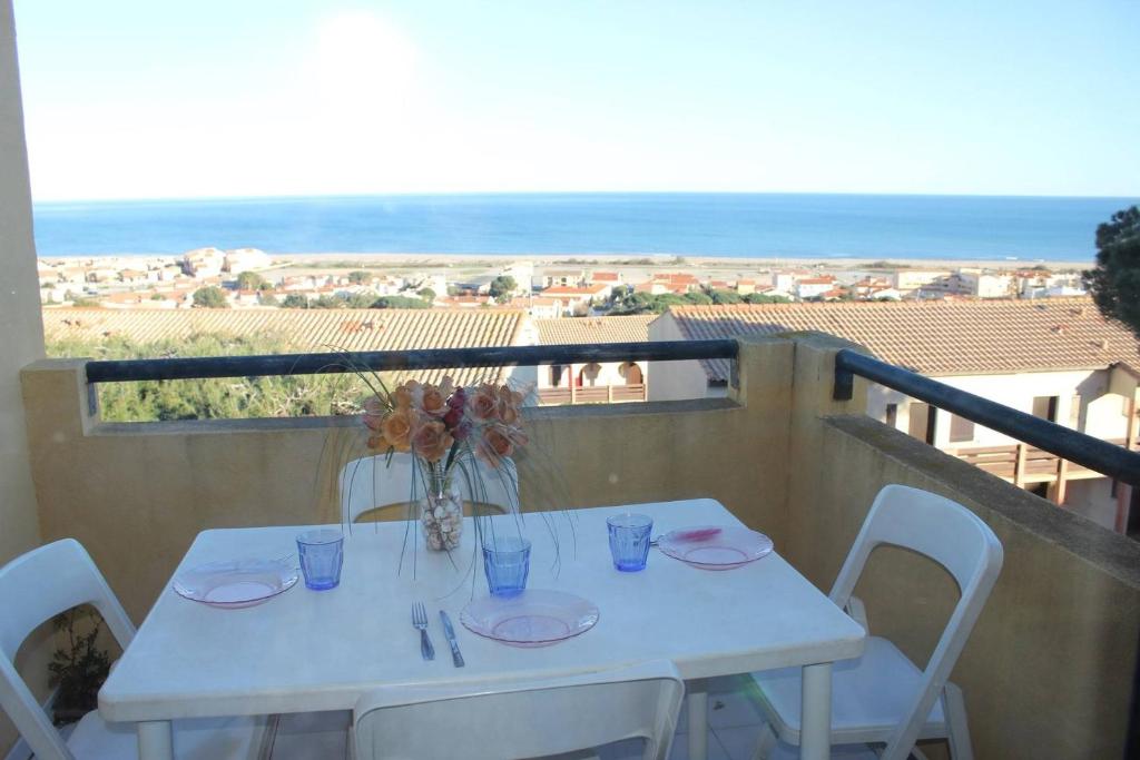 d'une table blanche avec des chaises et un vase de fleurs sur le balcon. dans l'établissement SP280-1142 Appartement 2 pièces - mezzanine SAINT PIERRE LA MER, à Saint Pierre La Mer