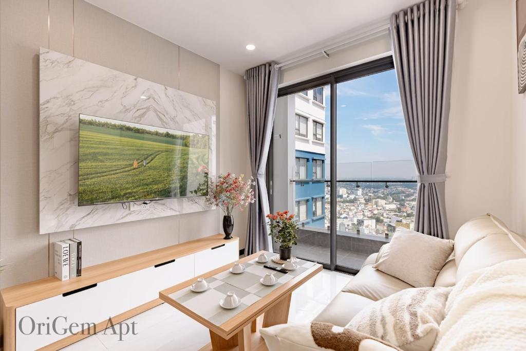 een woonkamer met een witte bank en een groot raam bij OriGem - Skyview Căn Hộ 2 PN in Thu Dau Mot