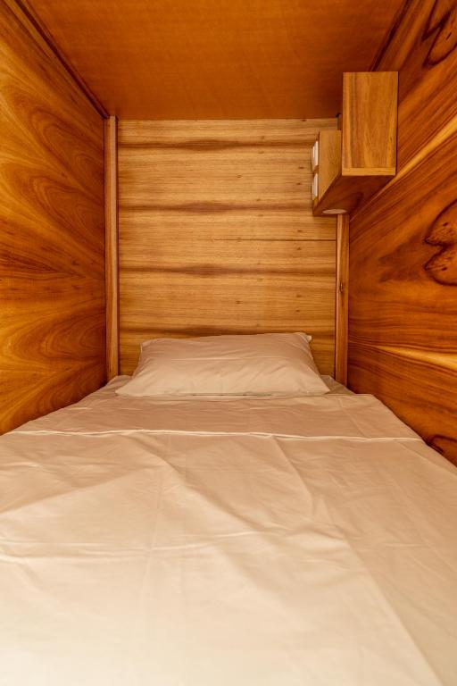 a bed in a room with a wooden wall at Lisbon Surf Hostel in Carcavelos