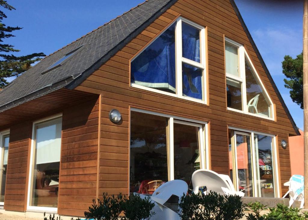 une maison avec des fenêtres et des chaises blanches dans l'établissement House with sea view and large garden for 8 people, à Plougasnou