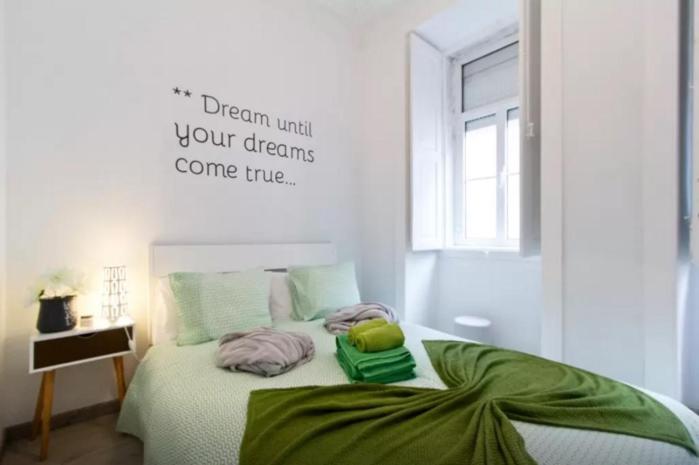 1 cama con almohadas verdes y un cartel en la pared en Lisbon Apartment Bairro Alto 2, en Lisboa