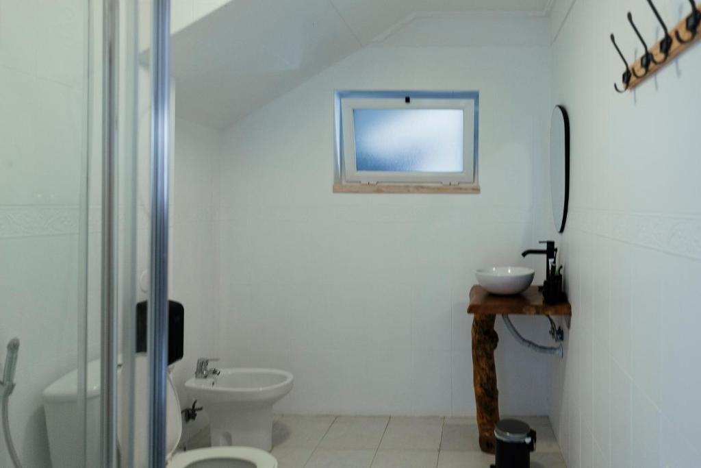a white bathroom with a toilet and a sink at Lisbon Surf Hostel in Carcavelos