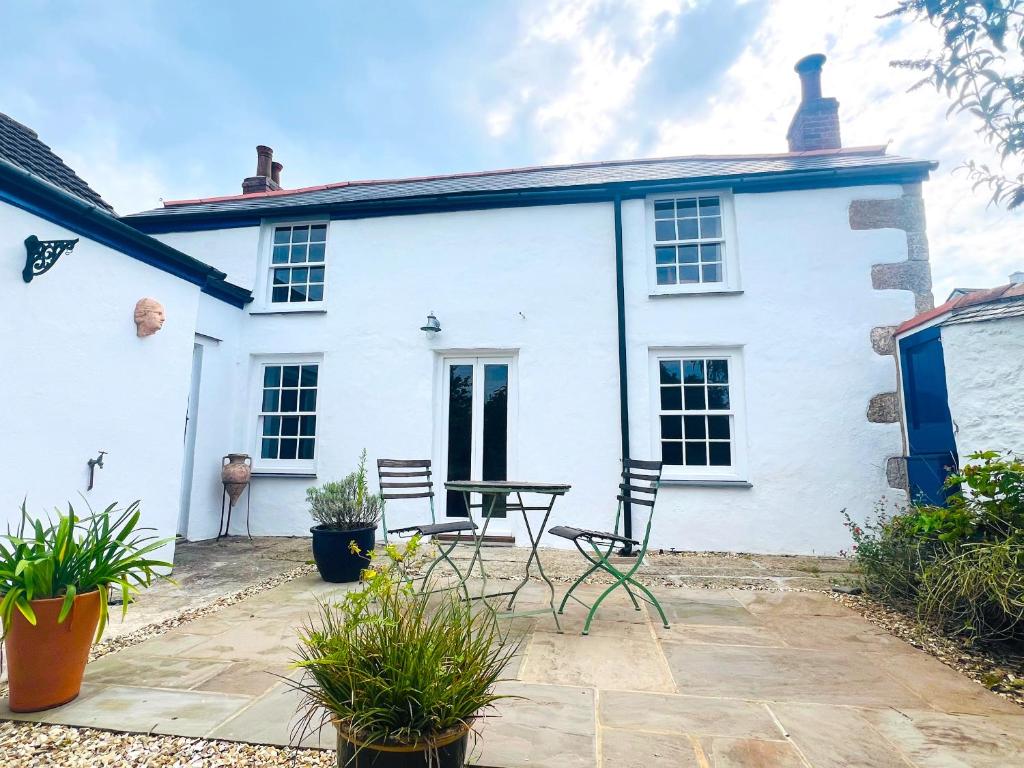 a white house with chairs and a table in front of it at Rose Cottage in Falmouth