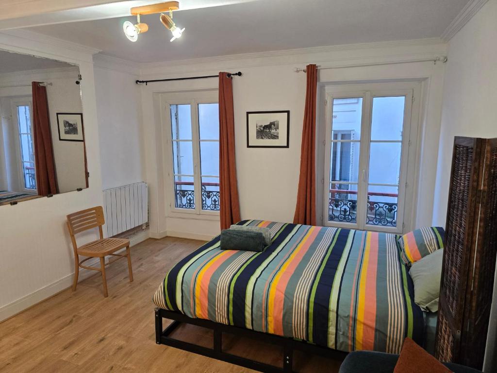 une chambre avec un lit, une chaise et des fenêtres dans l'établissement Confortable près des transports, à Paris