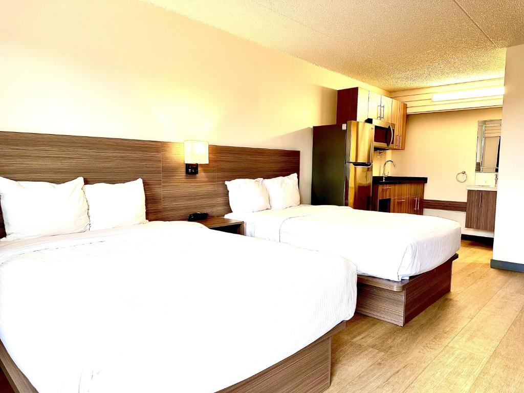 two beds in a hotel room with white sheets at Westport Inn in Grande Prairie