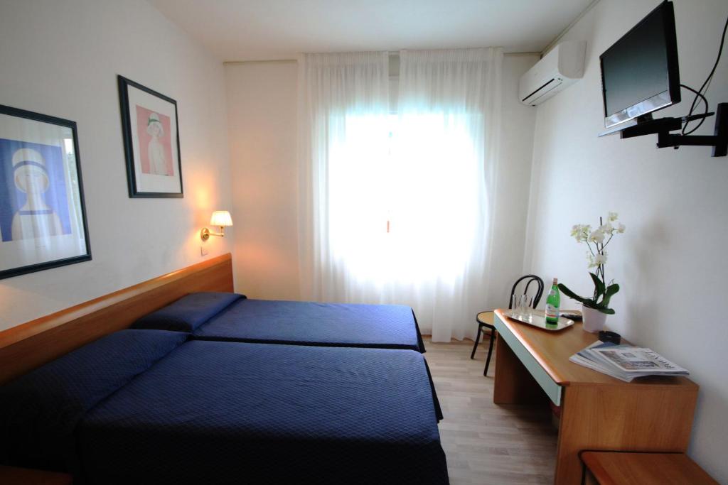 a bedroom with a bed and a desk and a window at Albergo Villa Gradita in Forte dei Marmi