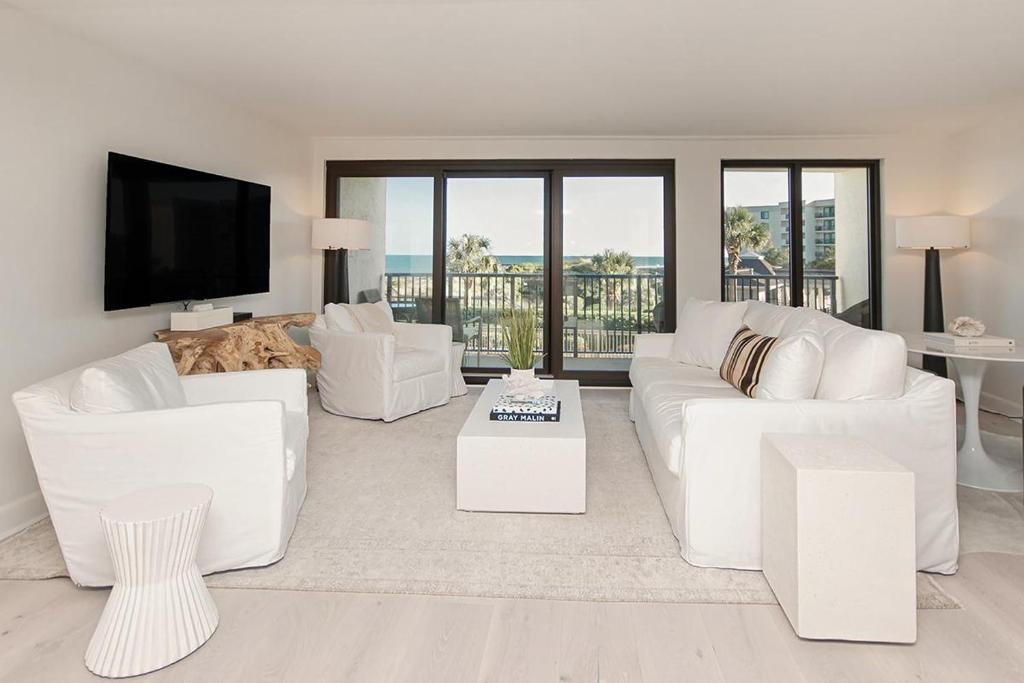 a living room with white furniture and a flat screen tv at Tranquil Getaway 2BR Ocean Views Onsite Amenities in Pawleys Island