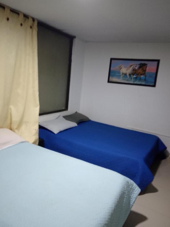 a bedroom with two beds and a picture of a cow at Continental Aparta Hotel Duitama in Duitama
