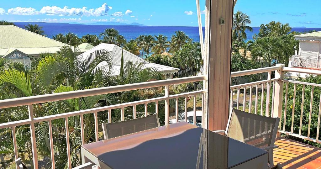 a balcony with a table and chairs and the ocean at Anse des Rochers-Studio Zabrico in Saint-François
