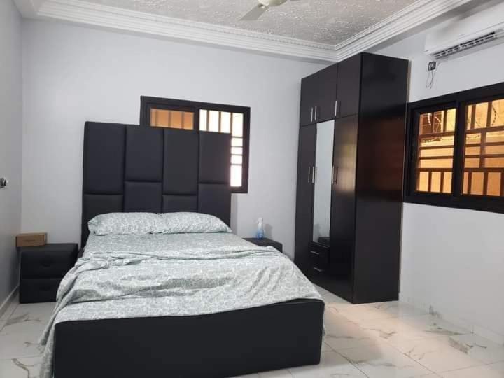 a bedroom with a large bed and black cabinets at Jolie Résidence de 03 chambres salon Légbassito in Atyémé