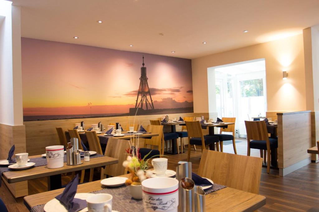 ein Restaurant mit Tischen und Stühlen und ein Turm an der Wand in der Unterkunft Gästehaus Janßen in Cuxhaven