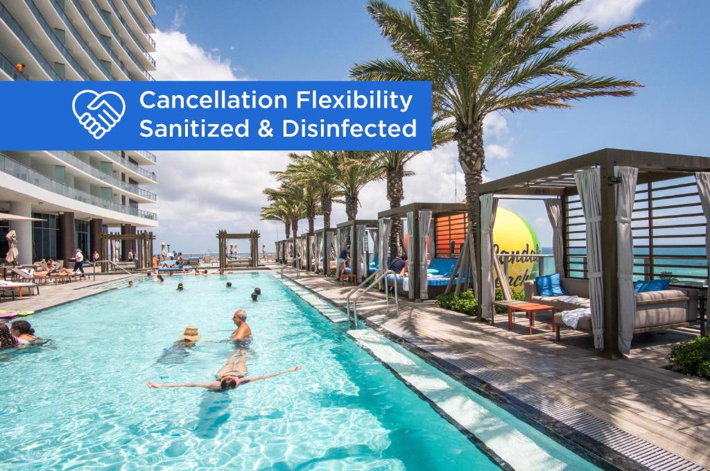 a group of people in a swimming pool with palm trees at Lyfe Beach Resort 3604 in Hollywood Beach