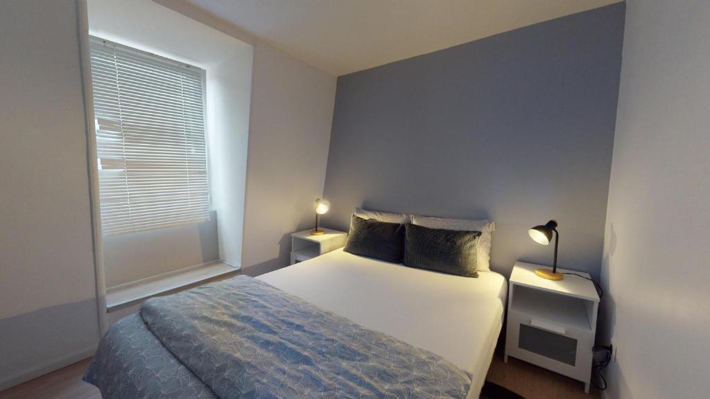 - une chambre avec un lit et une fenêtre avec deux lampes dans l'établissement Le Napoléon Mulhouse, à Mulhouse