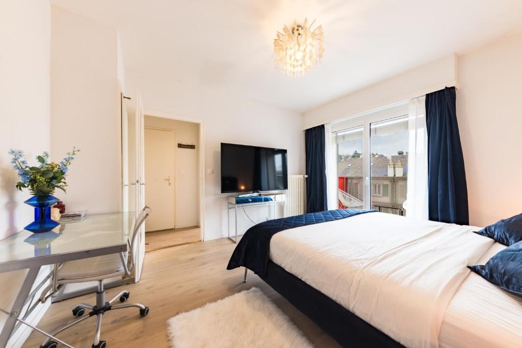 ein Schlafzimmer mit Bett, Schreibtisch und Fernseher in der Unterkunft Swiss Flat Rental in Lausanne
