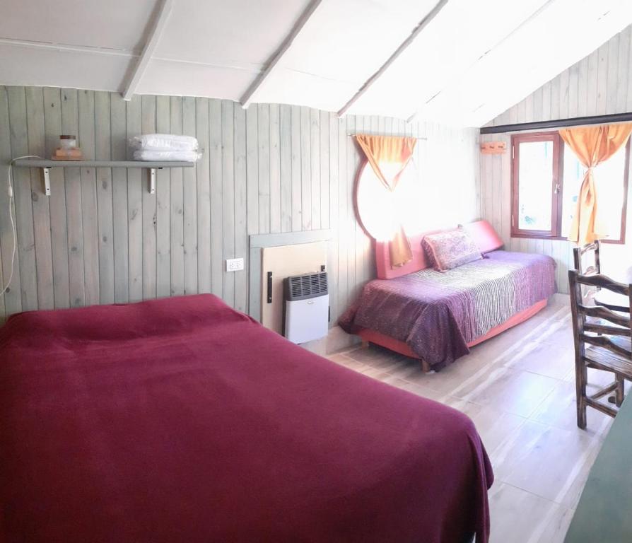 een slaapkamer met een bed en een stoel erin bij Cabaña El Búho, Lago Puelo in Lago Puelo