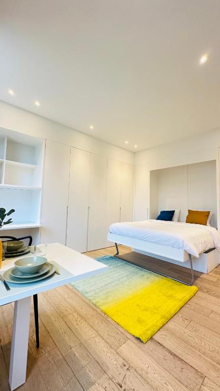 a bedroom with a bed and a table with a yellow rug at Studio Fischer à la Pétrusse 301 in Luxembourg