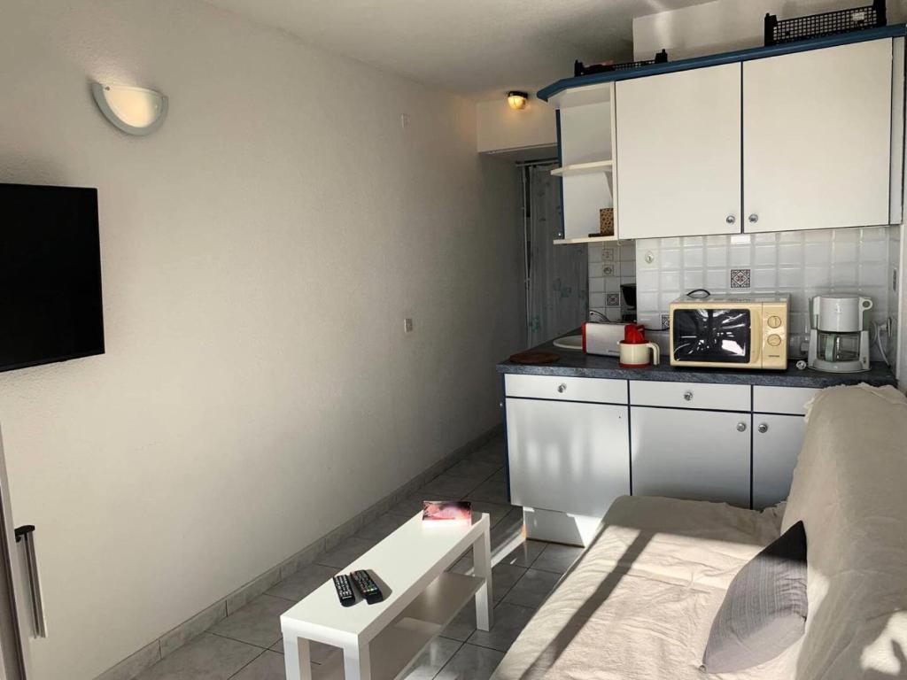 małą kuchnię z białymi szafkami i kuchenką mikrofalową w obiekcie Résidence Port Nature Colline 3 - Appartement T2 4 pers - Port Nature Colline 3 MAE-2874 w Cap d'Agde