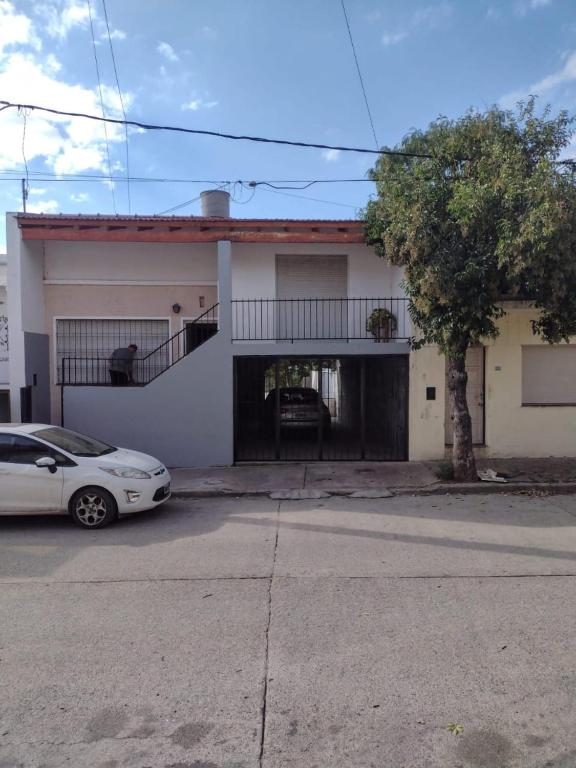 a white house with a car parked in front of it at CASA CENTRICA con SALIDA al RIO in Mina Clavero