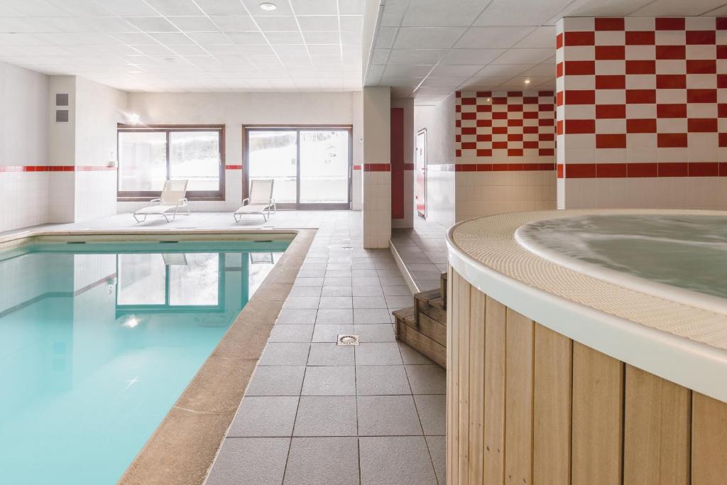 a swimming pool with a tub in a building at Lagrange Vacances Cybèle in Brides-les-Bains